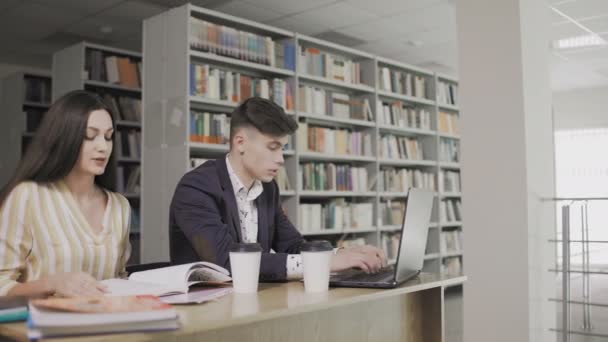 Два кавказских студента готовятся к экзамену в библиотеке — стоковое видео