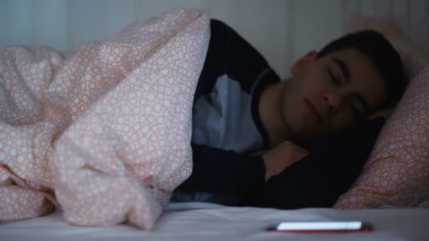 Hombre mirando su teléfono inteligente en la cama por la noche de cerca — Vídeo de stock