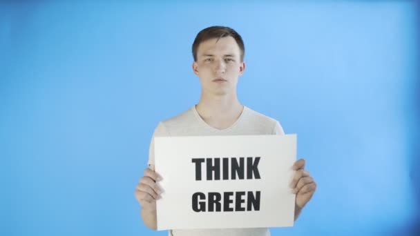 Jonge man activist met denk groene poster op blauwe achtergrond — Stockvideo