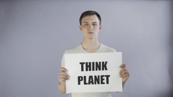 Молодой человек-активист с плакатом Think Planet на сером фоне — стоковое видео