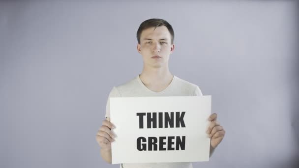 Mladý muž aktivista s think green plakát na šedém pozadí — Stock video