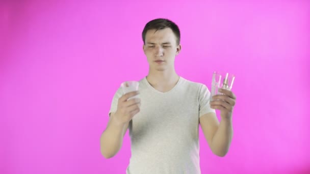 Активист-молодой человек с пластиковыми и стеклянными чашками на розовом фоне — стоковое видео