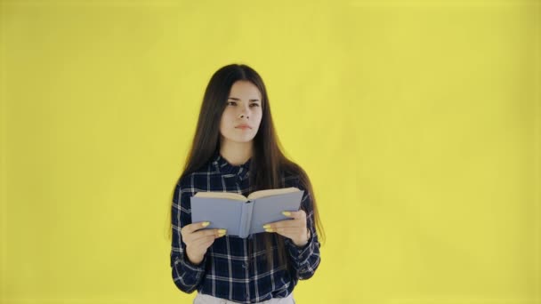 Beautifu tankeväckande flicka läser bok isolerad på gul bakgrund — Stockvideo