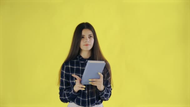 Schöne nachdenkliche Mädchen fertig Buch lesen isoliert auf gelbem Hintergrund — Stockvideo