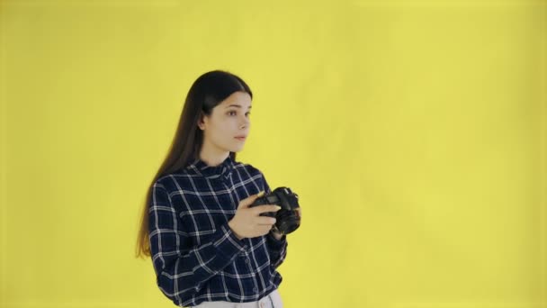 Chica joven está tomando una foto sobre fondo amarillo en el estudio — Vídeo de stock