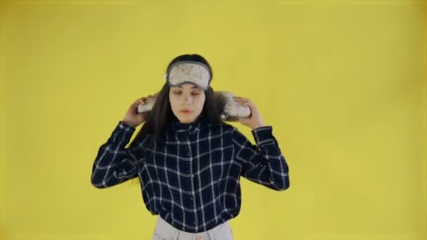 若い女性が睡眠マスクを脱ぎ、スタジオで黄色の背景にストレッチ — ストック動画