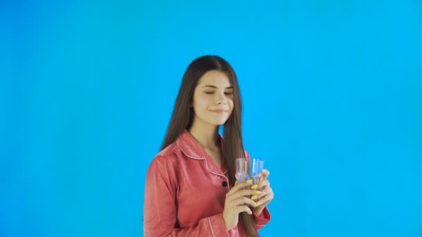 Caucasiano adolescente menina bebendo copo de água. Jovem mulher bebendo água de vidro no fundo azul no estúdio — Vídeo de Stock