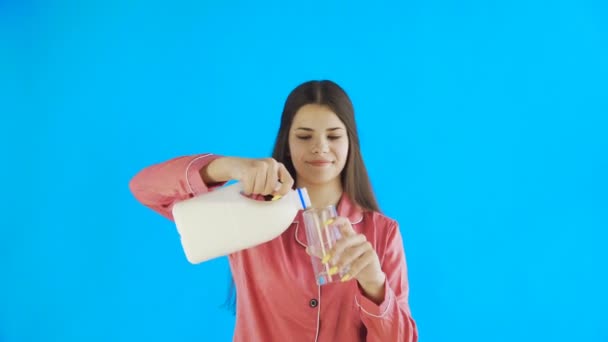 Ελκυστική νεαρή κοπέλα με πιτζάμες πίνει γάλα — Αρχείο Βίντεο