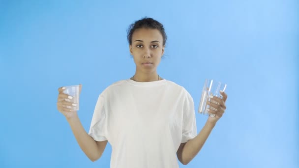 Activista afroamericana con copas de plástico y vidrio sobre fondo azul — Vídeo de stock