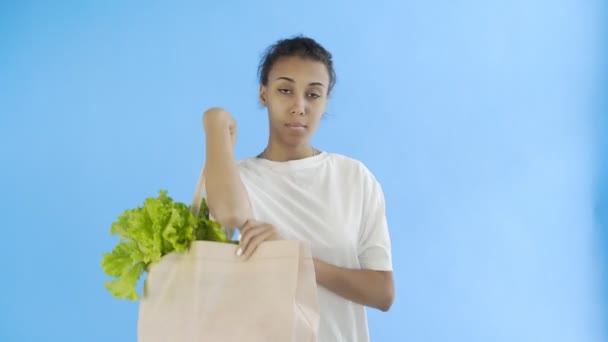 Mulher segurando saco com legumes no fundo azul — Vídeo de Stock