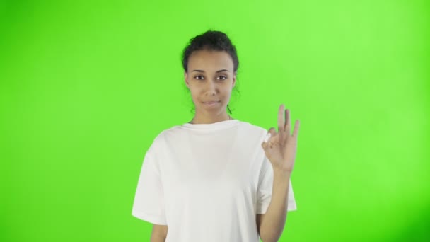 CuteAfro-American Girl está mostrando ok com dois polegares e sorrindo no croma chave fundo no estúdio — Vídeo de Stock