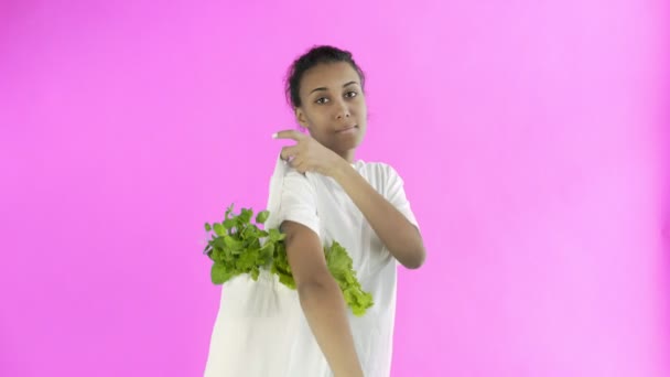 Frau hält Tasche mit Gemüse auf rosa Hintergrund — Stockvideo