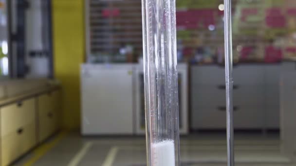 Работник лаборатории заполняет большую стеклянную колбу химикатами — стоковое видео
