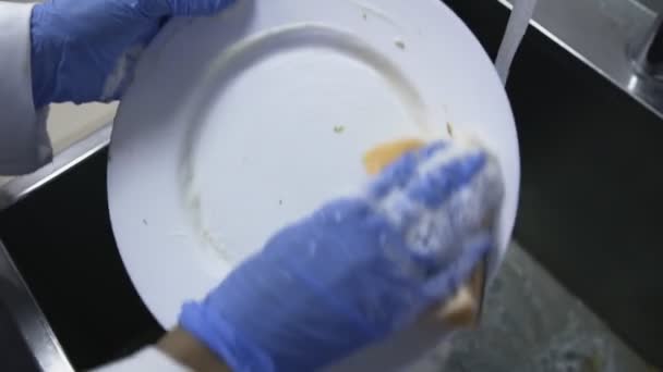 Молодая женщина в перчатках моет посуду на кухне, Концепция работы дома — стоковое видео