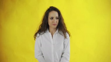 Ciddi bir genç kadının portresi başını sallıyor ve sarı arka planda izole edilmiş bir şekilde inkar ediyor.