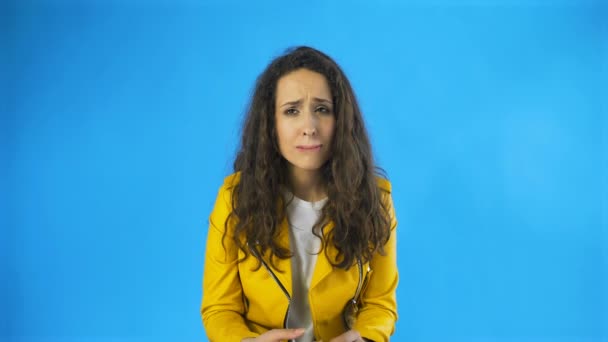 Besviken och en mycket ledsen ung kvinna nästan gråter i Studio med blå bakgrund. — Stockvideo