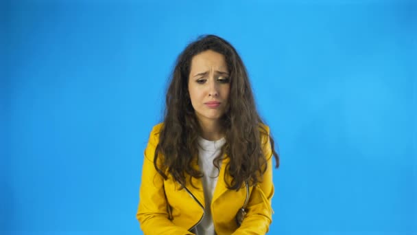 Дуже сумна молода жінка майже плаче в студії з блакитним тлом . — стокове відео