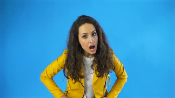 Eine sehr wütende und frustrierte Frau im Studio mit blauem Hintergrund. — Stockvideo