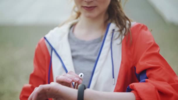 Frau wechselt Musik auf ihrer Smartwatch und trägt Kopfhörer — Stockvideo