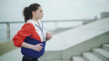 Merdivenlerden koşarak çıkan sağlıklı genç bir kadın. Dişi sporcu merdivenlerden tırmanıyor..