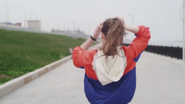 Vista trasera de la corredora femenina preparándose para correr y atándose el pelo — Vídeos de Stock