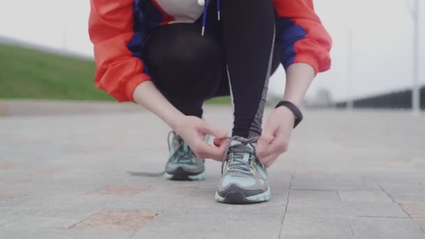 Joven mujer de fitness atando zapatillas Zapatillas de correr cordones en el parque . — Vídeo de stock