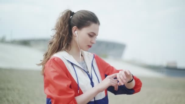 Jovem mulher correndo e verificando seus dados de treinamento cardio em seu relógio esporte . — Vídeo de Stock