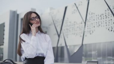 Akıllı telefon kullanarak gülen kızın portresi. Şehir parkında cep telefonu olan güzel genç bir kadın.