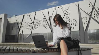 Dizüstü bilgisayarla çalışan, cep telefonuyla konuşan bir kadın.