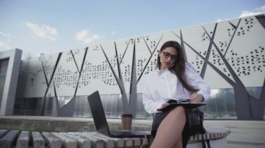 İş kadını telefonda konuşuyor ve ofisin yanındaki parkta belgelerle çalışıyor..