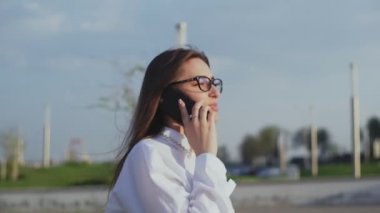 Toplantıya veya ofise yürürken akıllı telefondan konuşan çekici bir iş kadını.