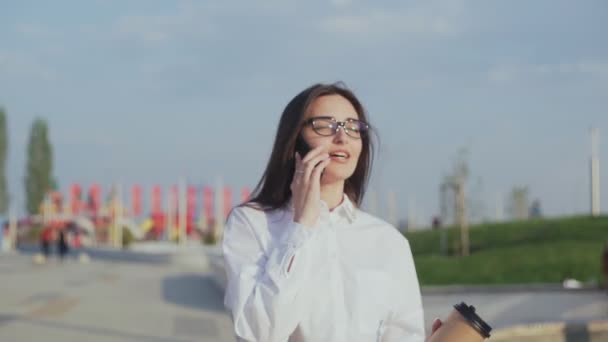 Bizneswoman idzie do biura z kawą i rozmawia przez telefon — Wideo stockowe