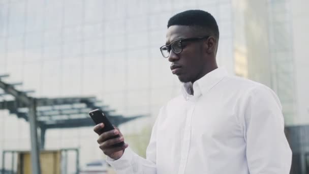Стильный афроамериканский бизнесмен в белой рубашке пьет кофе на улице возле офиса — стоковое видео