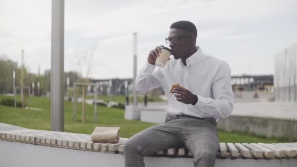 African Businessman Using Laptop Outdoors while Having Lunch — Stock Video