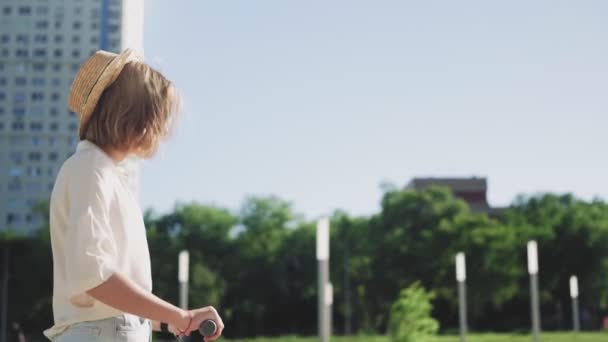 Jeune belle femme chevauchant un scooter électrique pour travailler, fille moderne, nouvelle génération, transport électrique, écologie, transport écologique, coucher de soleil, planche à roulettes électrique — Video