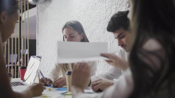 Nella sala riunioni il team di imprenditori, imprenditori e specialisti seduti al tavolo della conferenza discutono, risolvono problemi, utilizzano tablet, laptop, condividono documenti con statistiche, grafici — Video Stock