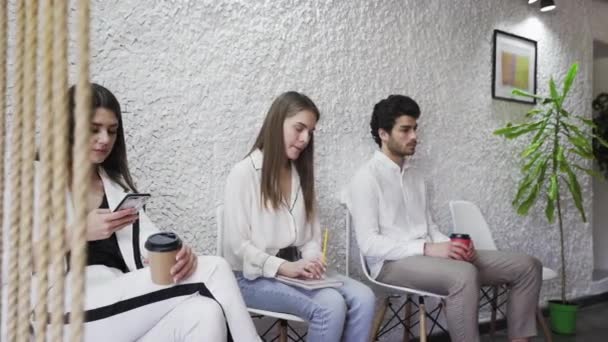 Группа безработных, сидящих в очереди в ожидании собеседования — стоковое видео