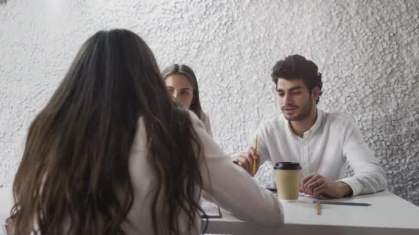 Tres jóvenes empresarios reunidos en la oficina discutiendo negocios en la oficina de la pequeña empresa — Vídeos de Stock