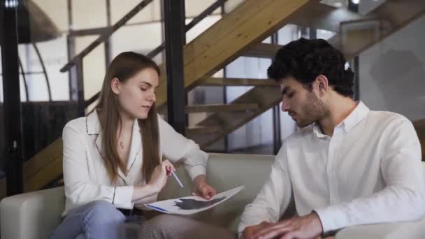 Zakenmensen discussiëren over de jaarrekening van het bedrijf terwijl ze op de bank zitten — Stockvideo