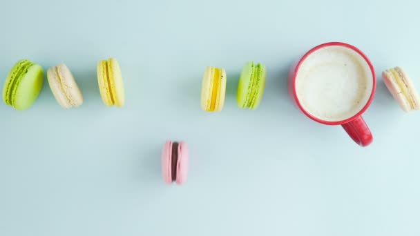 Macaroons ou macaron na superfície azul pastel com café em copo vermelho. — Vídeo de Stock