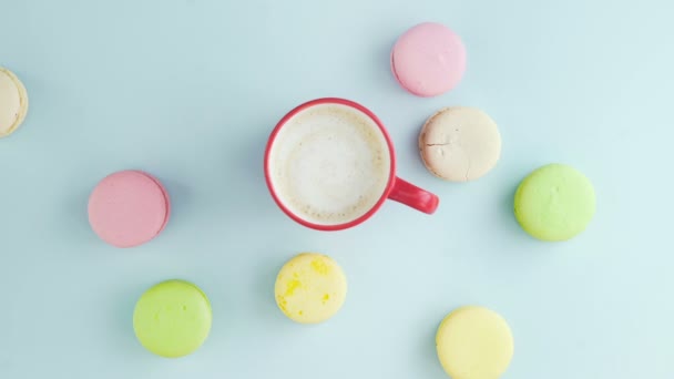 Macarons ou macarons sur une surface bleu pastel avec café en tasse rouge. — Video