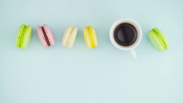 Macarrones o macarones en superficie azul pastel con espresso en taza blanca. — Vídeo de stock