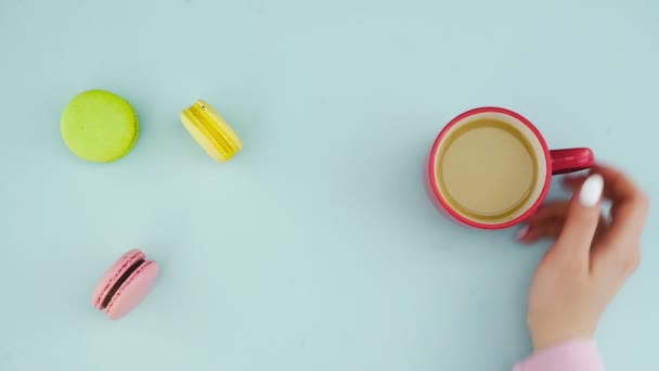 Macaroons ou macaron na superfície azul pastel com café em copo vermelho. — Vídeo de Stock