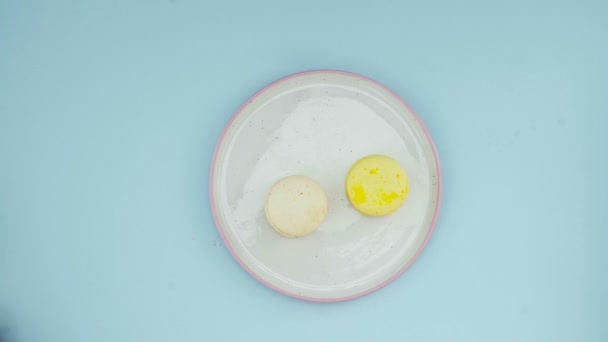 Macarrones de color dulce o macaron en plato blanco sobre superficie azul pastel . — Vídeo de stock