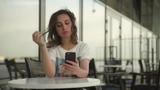 Mujer joven en auriculares mirando el teléfono inteligente — Vídeos de Stock