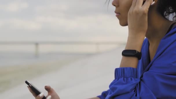Afro-americká běžkyně se sluchátky a smartwatch odpočinku po spuštění v parku — Stock video
