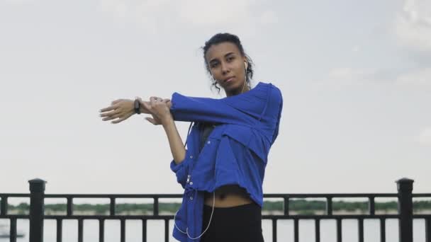 Joven mujer afroamericana en auriculares realiza estiramiento y calentamiento antes de correr en el parque — Vídeos de Stock