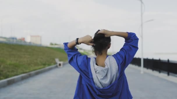 Женщина-бегунья готовится бежать и завязывать волосы — стоковое видео