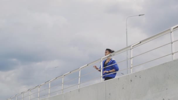 青いジャケットを着たアフリカ系アメリカ人のランナーの女性が走り終えた — ストック動画