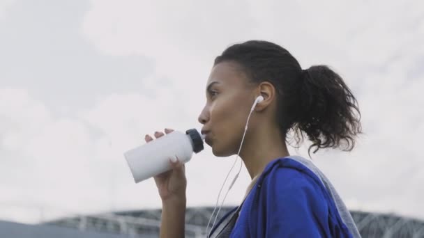 Afro-americká běžkyně Pití vody nebo izotonické Po spuštění. Portrét Fitness žena pitná voda z láhve. — Stock video